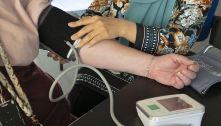 Henkilö laittaa verenpainemittarin mansettia toisen henkilön käteen.