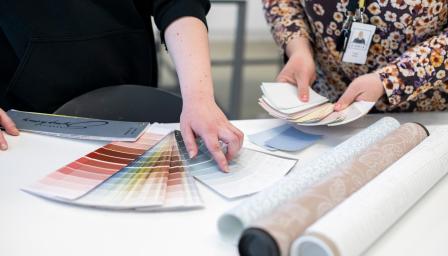 Opiskelija ja ohjaaja selaavat painoväriviuhkaa.