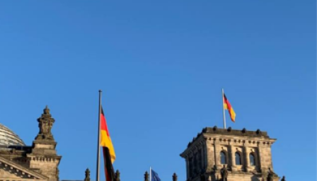 Vanha rakennus sinistä taivasta vasten ja Saksan lippu.