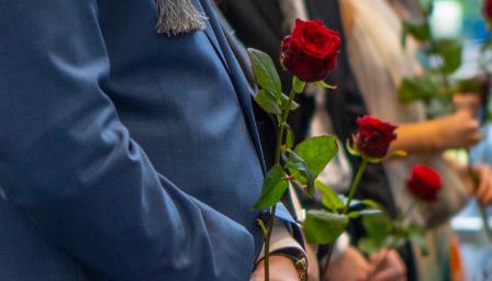 Rajaus ruusuista valmistuneiden opiskelijoiden kädessä.