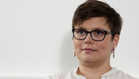 Anna Pousi katsoo kameraa ja hymyilee.