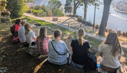 ryhmä istuu puistossa joen varrella