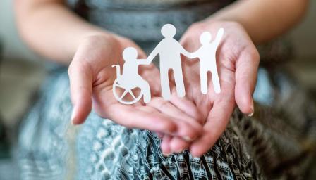  Paperista leikattuja ihmishahmoja henkilön kämmenellä.