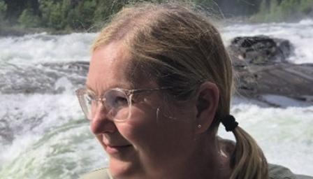 Kouluttaja Pirkko Taipaleen kuvan taustalla koski ja metsää.