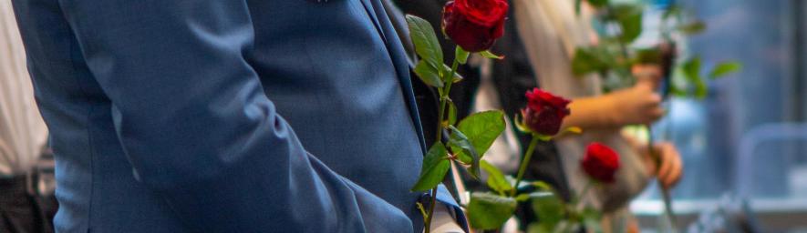 Rajaus ruusuista valmistuneiden opiskelijoiden kädessä.