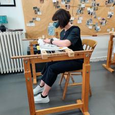 Henkilö kirjoaa kultalankaa.