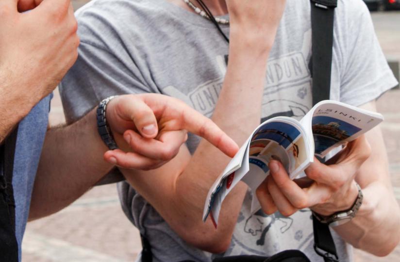 Turistit katsovat kaupunkiopaskirjaa mietteliäinä.