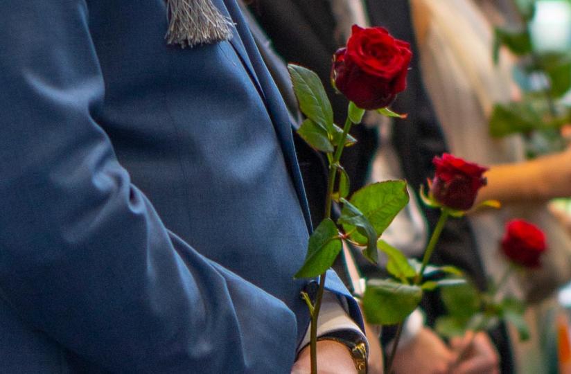 Rajaus ruusuista valmistuneiden opiskelijoiden kädessä.