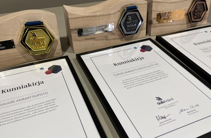 Kuvassa kunniakirjoja ja palkintoja kolme kappaletta.