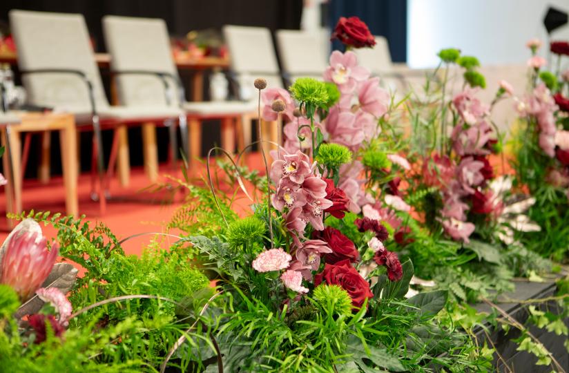 Kukkia lavan edustalla. Takana näkyy rivi tuoleja.