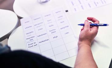 Opiskelija harjoittelee suomen kielen sanoja paperilla.