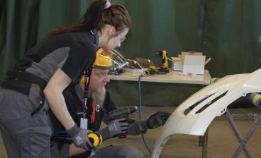 Opiskelija ja opettaja korjaavat auton etupuskuria