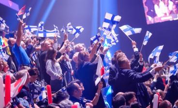 Suomen lippuja heilutetaan katsomossa.