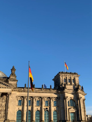 Vanha rakennus sinistä taivasta vasten ja Saksan lippu.