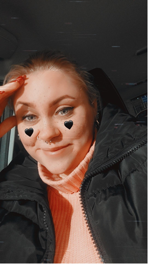 Helena Metsänranta katsoo kameraan. Hänellä on poskipäissä piirretyt mustat sydämet. Hän hymyilee.