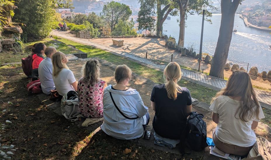 ryhmä istuu puistossa joen varrella