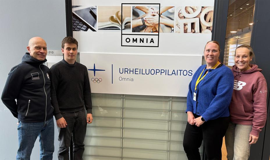 Neljä ihmistä seisoo vierekkäin ja katsoo kameraan. Heidän välissään on seinä, jossa on Omnian logo sekä teksti Urheiluoppilaitos.