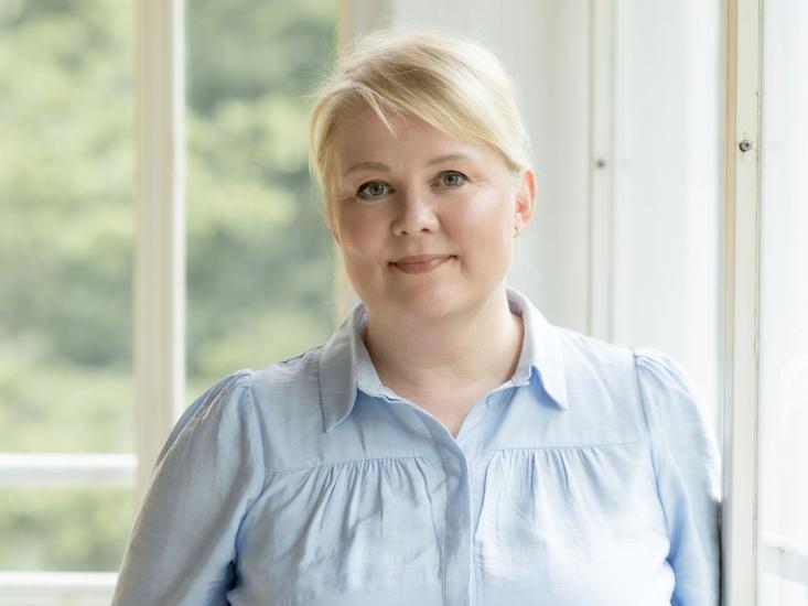 Kuvassa kouluttaja Sirpa Karvonen ikkunan edessä.