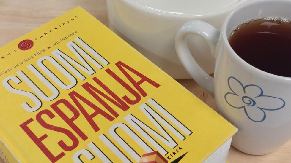 Kuvassa on sanakirja ja kahvikuppi