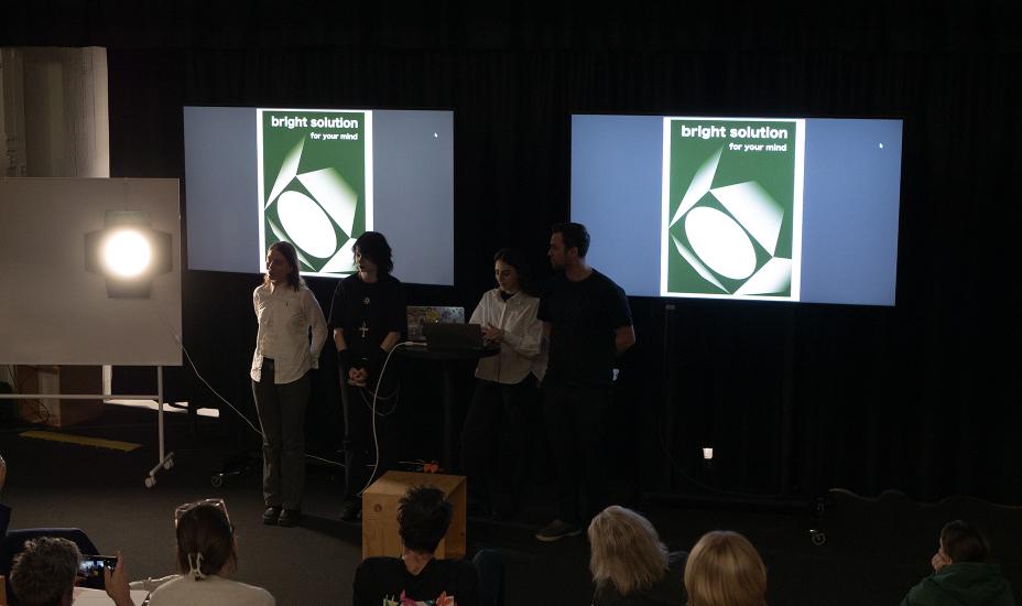 Yleisössä istuva henkilö, jonka selässä näkyy Bright Solution -logolla varustettu musta t-paita.