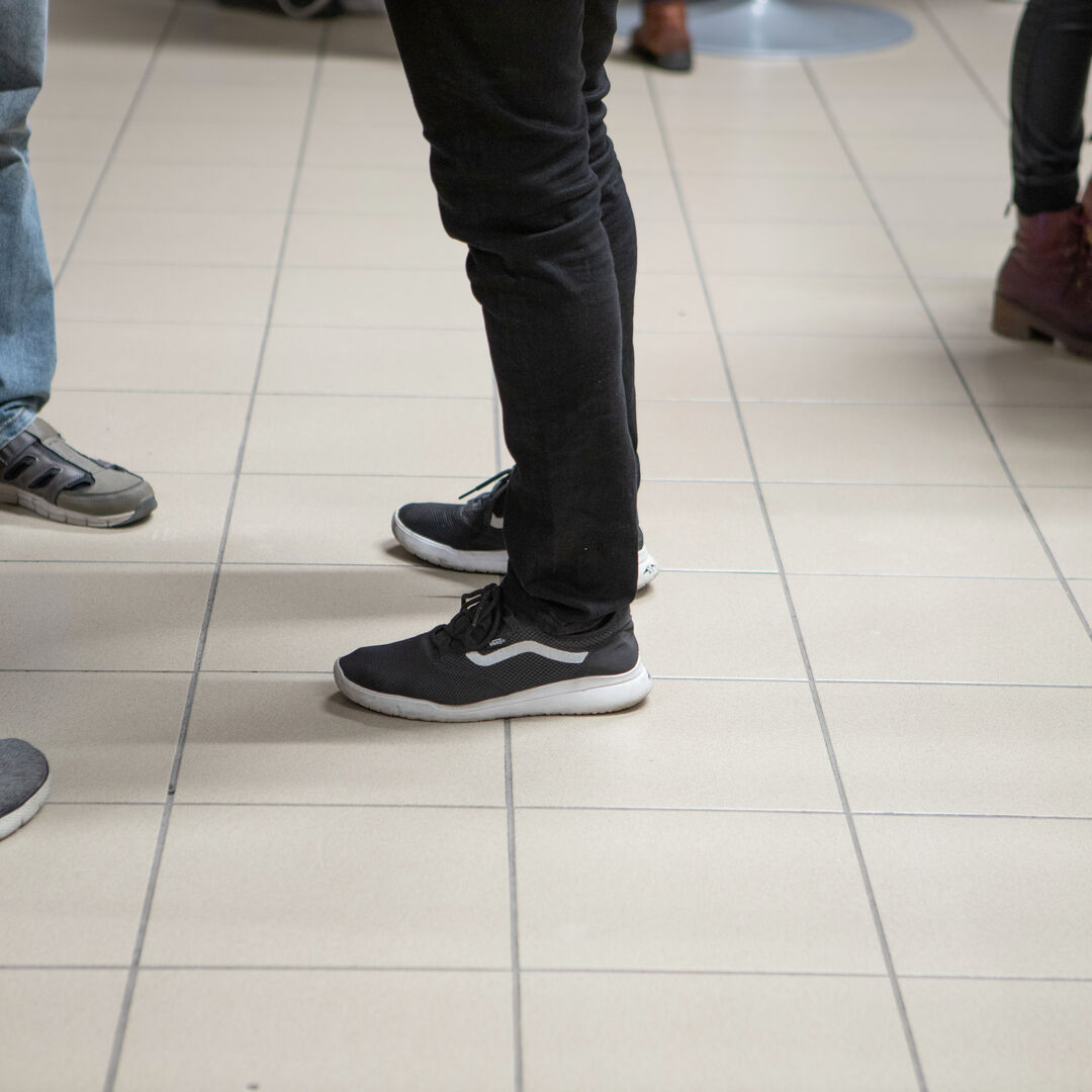 keskustelevien ihmisten jalat vaalealla ruutukuvioisella lattialla.