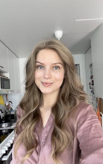 Henkilö ottaa selfien vaaleassa keittiössä, taustalla kodin sisustusta ja keittiötarvikkeita.
