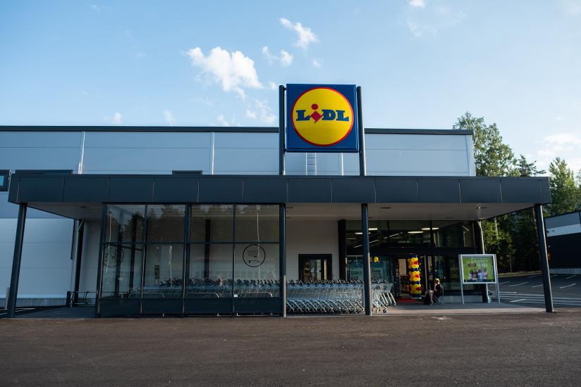 Lidl-myymälän ulkonäkymä, jossa näkyy sisäänkäynti, ostoskärryt ja kaupan kyltti rakennuksen katolla.