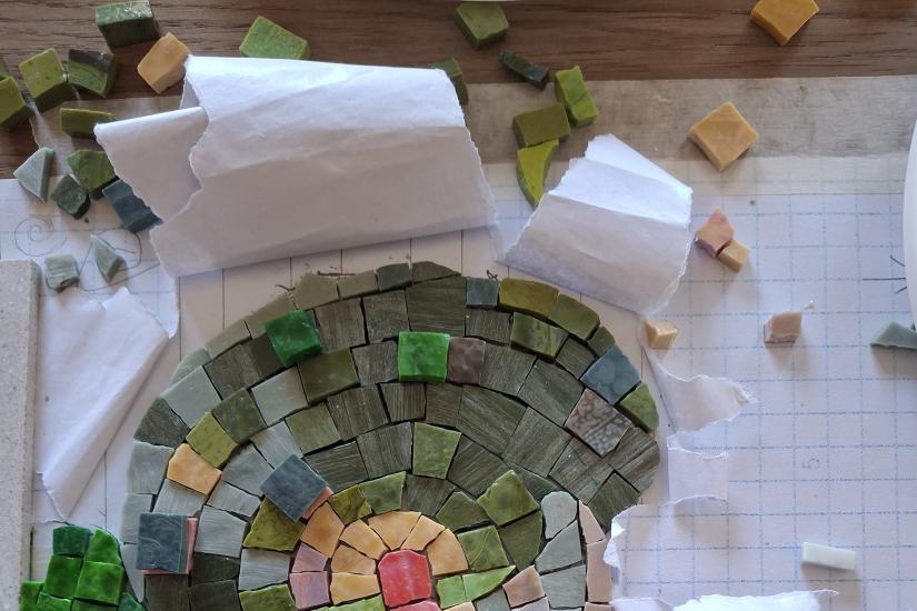 Mosaiikkityötä suunnitellaan ruutupaperille vihreän, keltaisen ja punaisen sävyisistä paloista.